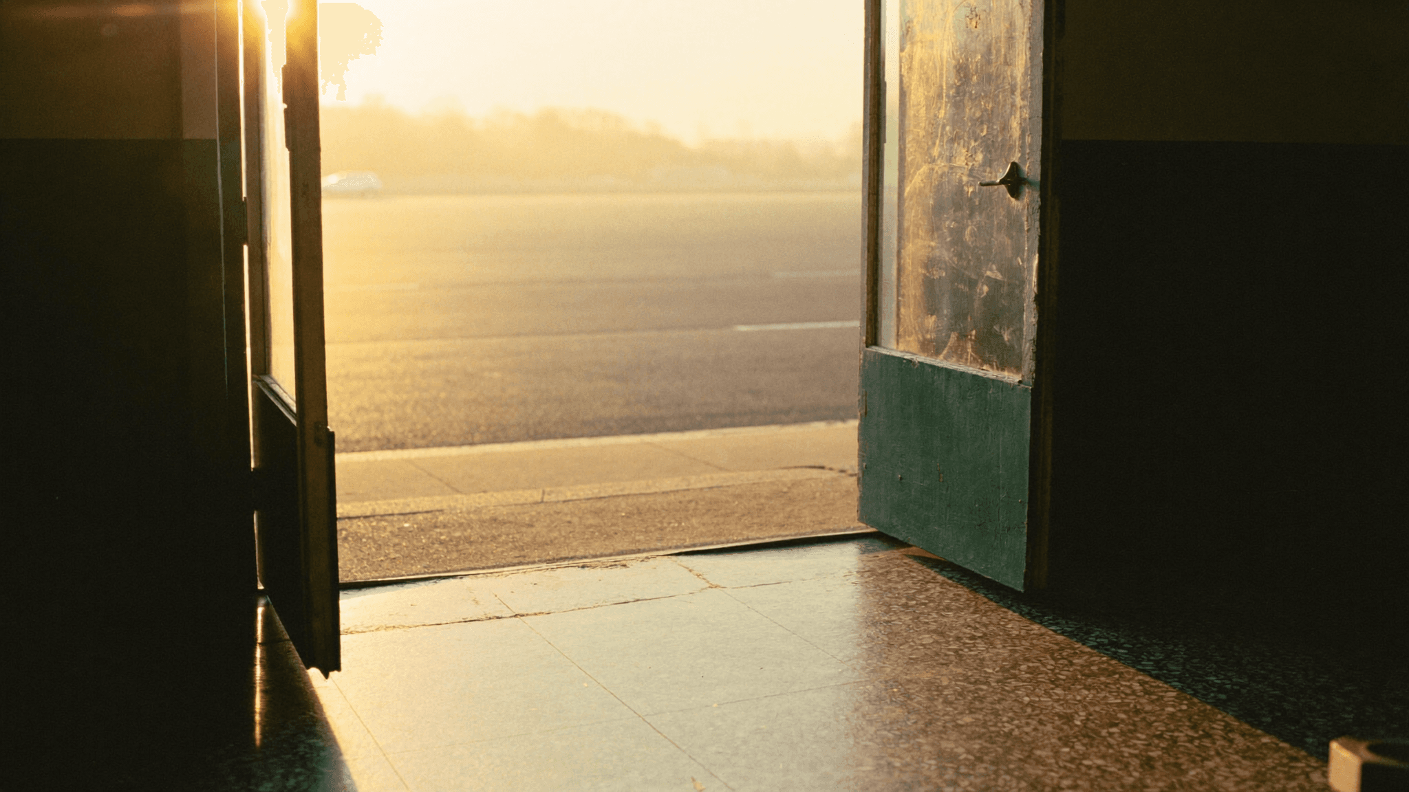 An open shophouse door at sunrise, warm light falling across a terrazzo floor.